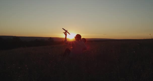 Dreaming duże syna z tatą o zachodzie słońca, grając z czerwony samolot, wydatków dobry czas razem, motyl mucha okolicy, doskonały widok. — Wideo stockowe