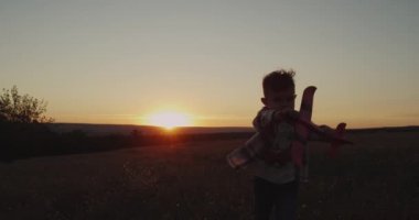 Kaçarken alanda ve büyük bir uçak ile günbatımında oynayan sevimli çocuk. 4k