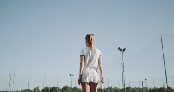 Со спины спортивная юная леди готовится к началу теннисной игры, на теннисном корте . — стоковое видео