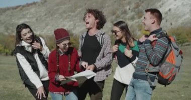 Kız ve erkek olan bir şirket bir yolculuk zaman var, bir harita için sergi, doğru hedef bulmak için kullanma dağ ortasında gülümseyen yüzler.