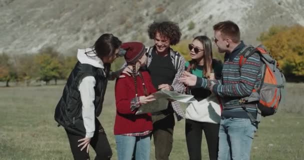 A multicultural friends using a map try to find the right way to the next destination , in the middle of mountain very equipped for trip young guys. — Stock Video