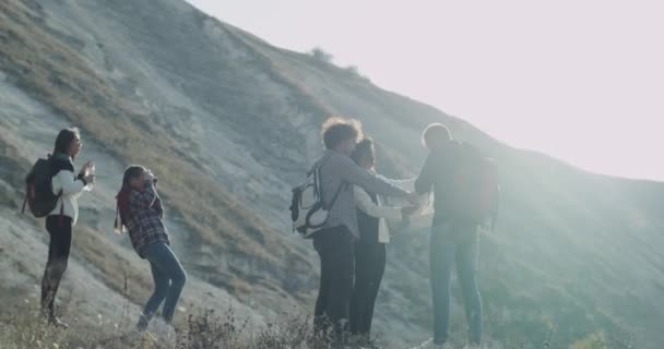 Skupina přátel, různých ras mají čas přestávek na vrcholu hory, jsou obrázky pitné vody a dalších při pohledu přes mapu, se snaží najít správnou cestu k návratu. — Stock video