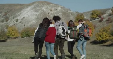 Arkadaşlar birbirlerine sarılma alanda yürüyüş çanta ile dağ gezisinde grup. Kırmızı epic vurdu