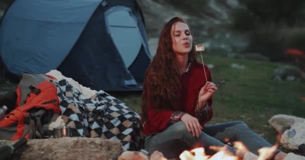 Beautiful charismatic lady , closeup eating marshmallows at campfire , in the night. — Stock Video