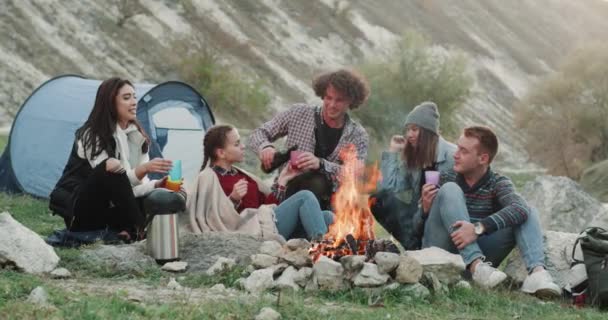 Amigos en medio de la montaña tienen un viaje, sentado frente a la hoguera y beber vino, vista increíble, tiempo de fogata. 4k — Vídeo de stock