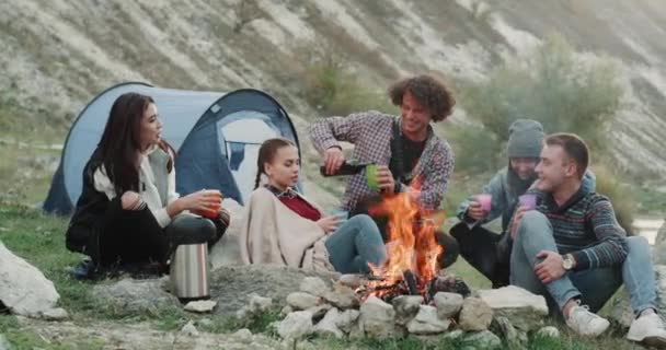 Vijf vrienden op camping kampvuur drinken wijn zit, ze hebben een gelukkige stemming. geschoten op het rode epos. 4k — Stockvideo