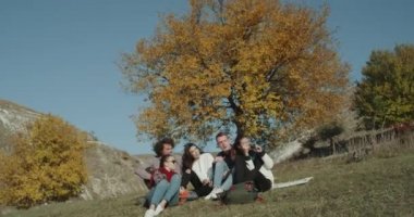 Çok kültürlü arkadaşlar güzel bir sergi doğa üzerinde onlar kadar fotoğraf çekmek bir sonu büyük bir renkli ağacı altında var.