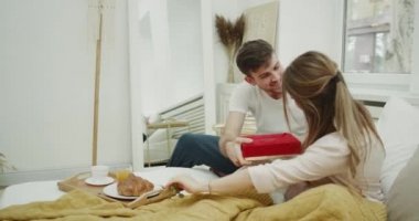 Çok mutlu genç bayan var o güzel bir hediye onun adamdan yatak odasında bir mutlu sabah.