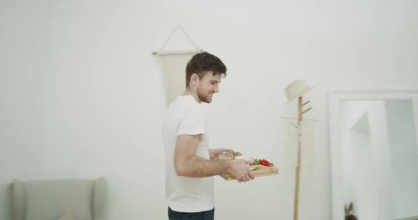 Junger Mann bereitet Frühstück für seine Frau zu und überrascht seine Partnerin im Schlafzimmer. — Stockvideo