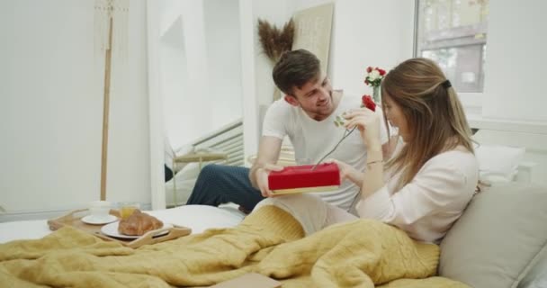 Regalo de la mañana en la cama de un chico joven a su señora, son muy felices . — Vídeos de Stock