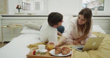 Sabah alarak güzel çift yatakta kahvaltı ve onlar gülümseyen ve mutlu harcama inanılmaz zaman bir dizüstü bilgisayar arasında bir göz var.