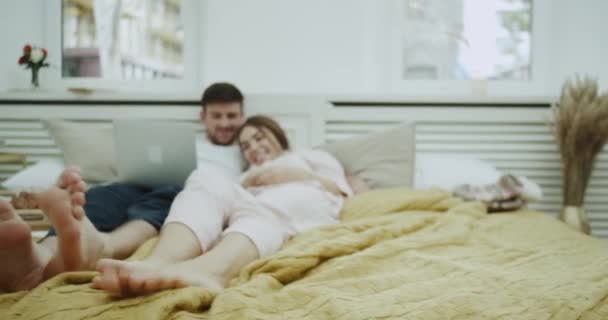 Pasar tiempo romántico juntos pareja joven en la mañana viendo algo de cuaderno en la cama . — Vídeos de Stock