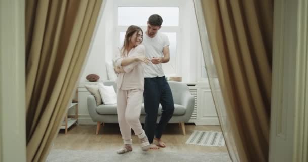 Ambiente acogedor en la sala de estar pareja bailando romántico en pijama. 4k — Vídeos de Stock