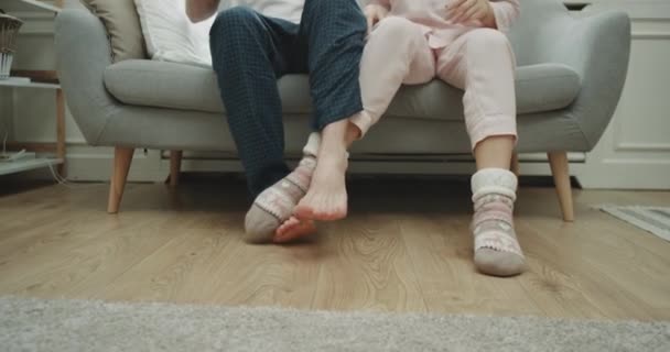 Tempo divertido para um casal em casa no sofá brincando com as pernas, em pijama closeup captura jogando pernas. 4k — Vídeo de Stock