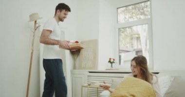 Sabah güzel bir çift yatakta, eşi, mutlu İçecek suyu ve kahve için bir gül veren adam kahvaltı var.