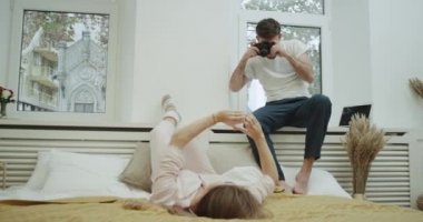 Genç bayan pijama modern yatak, çok güzel bir atmosfer onun erkek arkadaşı için bazı fotoğraflar için poz.