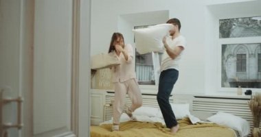 Modern bir yatak odasında güzel bir çift deli süre yatak gülümseyen üzerinde yastıkları ile oynama ve iyi bir ruh hali var.