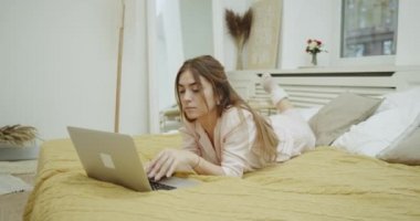 Sevimli bayan pijama modern yatak odasında yatağın üstünde onun defter üzerinde vakit akşam.