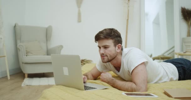 Férfi pizsama, és dolgozik a notebook, modern hálószoba ágy megállapításáról. — Stock videók