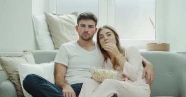 İzlerken tv genç çift kanepede oturan ve bir pijama giymiş patlamış mısır büyük bir tabak yemek sabah.