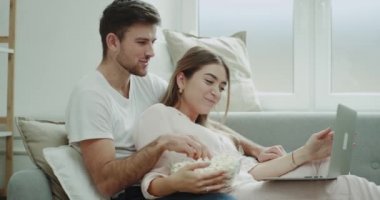 İnanılmaz zaman çift birlikte ev--dan laptop film izlerken ve patlamış mısır, modern oturma odasında iki pijama yeme harcama..