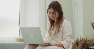 Sabahları bir Bayan Pembe pijama notebook, modern tasarım üzerinde oturma odasında çalışma.