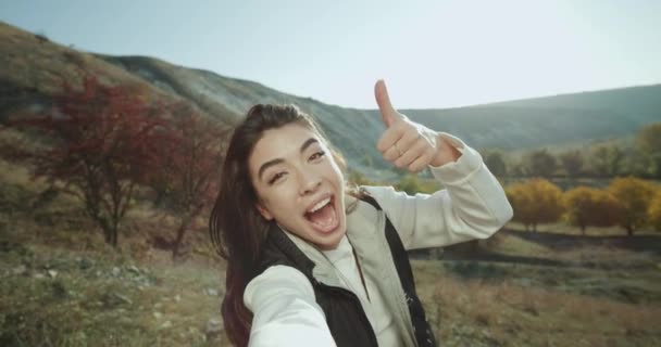 Grande sonriente hermosa morena filmando su auto en un viaje por la naturaleza mostrando la belleza de la naturaleza . — Vídeos de Stock