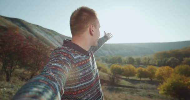 Un chico pelirrojo en un viaje filmando su auto y tomando algún video para recuerdos en la cima de las montañas. tiro en épica roja — Vídeos de Stock