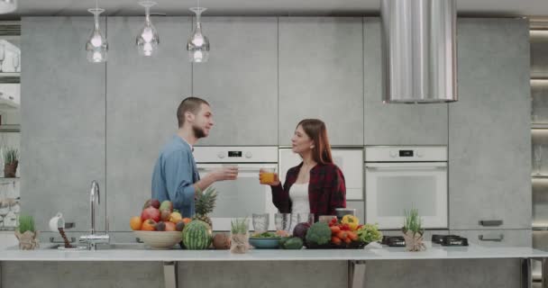 Manhã na cozinha nossa jovem família se enforcando e bebendo suco de laranja tomar um café da manhã saudável. 4k — Vídeo de Stock