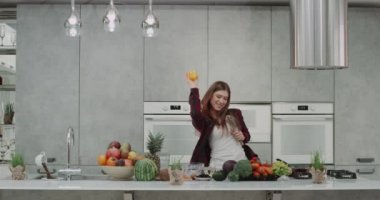Güzel bir kadın iyi bir ruh hali sabah o dans ve modern bir mutfak bir büyük mutfak ada kahvaltısını yaparken bizim sarı biber ile oynama var