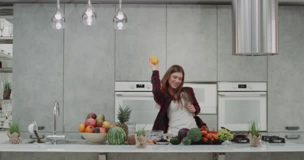 Bella donna hanno un buon umore al mattino lei ballare e giocare con il nostro pepe giallo mentre la sua colazione in una cucina moderna con una grande isola di cucina — Video Stock