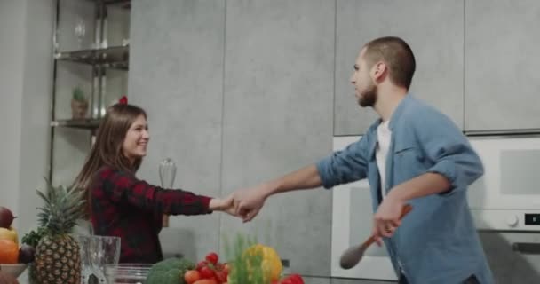 Pareja joven por la mañana tienen un buen estado de ánimo mientras hacen el desayuno que están bailando en una cocina moderna . — Vídeo de stock