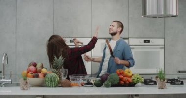 Sabahları bir modern mutfak çift onlar müzik ve mutlu dacing ve Mutfak el mikseri ve iyi bir harcama bir pan kullanarak şarkı dinlemek kahvaltı hazırlamaya başlamadan önce iyi bir ruh hali var