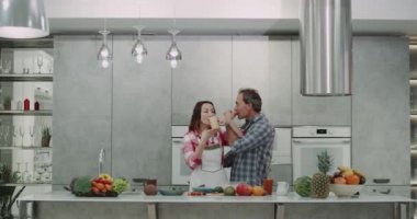 Olgun çift mutfakta kahvaltı güler yüzlü içme ve çok hoş, güzel gri mutfak arkasında öpüşme süre Romatinc.
