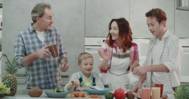 Karizmatik aile birlikte dört aile üyeleri birlikte iyi vakit içinde modern bir mutfak, yemek kahvaltı hafta sonu. Kırmızı epic vurdu. 4k