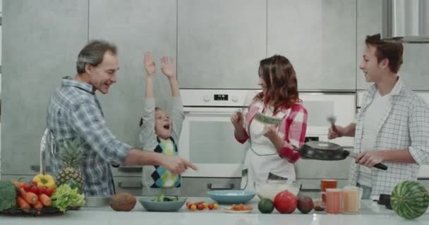 I genitori maturi ei loro figli hanno un bel insieme in una cucina moderna dacing durante la preparazione della colazione . — Video Stock