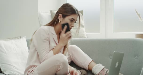 Sur le canapé gris dame commander quelque chose au téléphone à l'aide d'un ordinateur portable . — Video