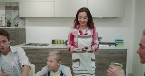 Por la mañana una linda familia pasar un buen rato juntos mientras toma la comida, mujer trae toda la comida en la mesa hombre tiene que trabajar mientras toma su desayuno en su computadora portátil . — Vídeo de stock