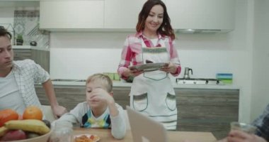 Çok çekici Olgun Anne onun iki çocuğu ve kocası ve mutlu bir tabak alıp akşam yemeği masaya getirerek kahvaltı hazırlamak.