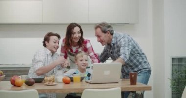 Birlikte laptop ve mutlu bir maç izlerken kahvaltı alarak eller modern mutfakta havaya iken sabah güzel bir aile. 4k