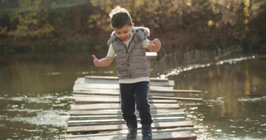 Sevimli küçük bir çocuk köprüde gölün yürüyor. 4k
