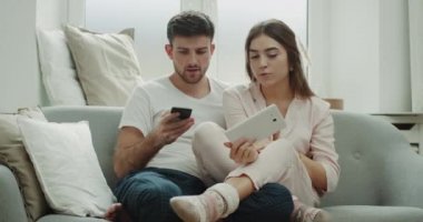 Sipariş zaman genç bir çiftin bir pijama giymiş sabah ve mutlu telefon, etrafında rahat tarzı siparişinden yapma.