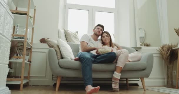 Belo design de casal sala de estar tem tempo relaxante assistindo tv e comer pipocas vestindo um pijama . — Vídeo de Stock