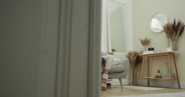 Tempo de filme para um jovem casal de pijama passar um dia juntos no sofá eles estão muito felizes comendo pipocas. 4k — Vídeo de Stock