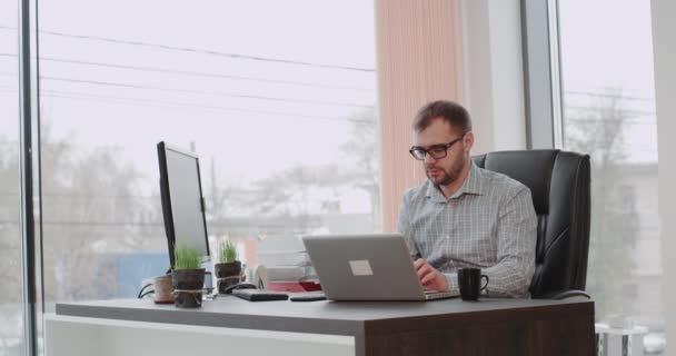 Karizmatik genç müdürü konuşan ve dizüstü bilgisayarda aynı anda çalışan Office mutlu iyi bir gün var. — Stok video