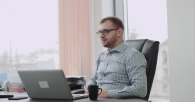 İş kameraya bakarak ve bir büyük gibi gösterilen evinde genç işadamı.