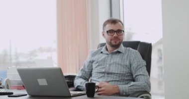 Panoramik bir ofiste bir banka müdürü straight kamera ve bir büyük gibi büyük sandalyesinde oturan gösterir arıyorum iyi bir ruh hali var. 4k