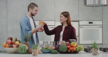 Sabah genç aile modern mutfak kadın ve partneri birbirlerini öpmeye ve sağlık güler yüzlü hazırlamak başlangıç yakalayan. 4k