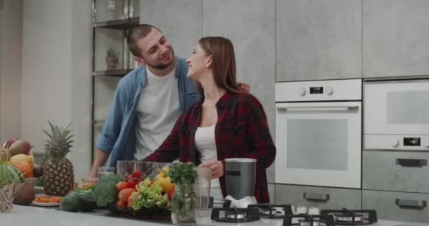 Una joven pareja por la mañana bebiendo sano beber hacen batidos y degustación feliz juntos, en una cocina moderna . — Vídeo de stock