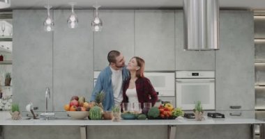Erkek ve kadın her diğer ve yapım güler yüzlü kahvaltı için modern mutfakta dostum öpüşme sabah içecekler portakal suyu.